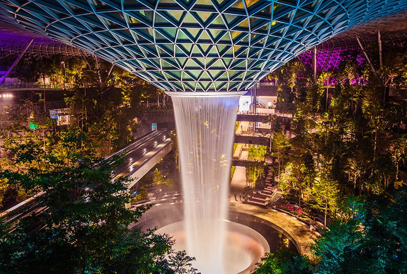 Night attractions in Singapore: admire the lush gardens and gushing Rain Vortex indoor waterfall. Jewel Changi Airport / TIH