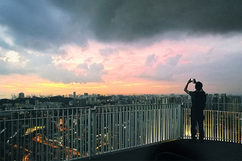 Photo of a man capturing the night view at The Pinnacle @ Duxton at dusk.