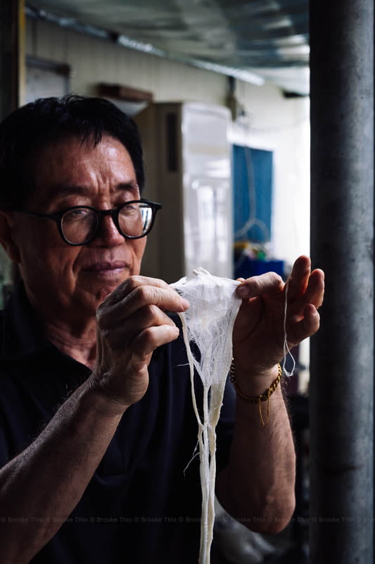 The guide shows visitors a softened piece of paper mulberry pulp.